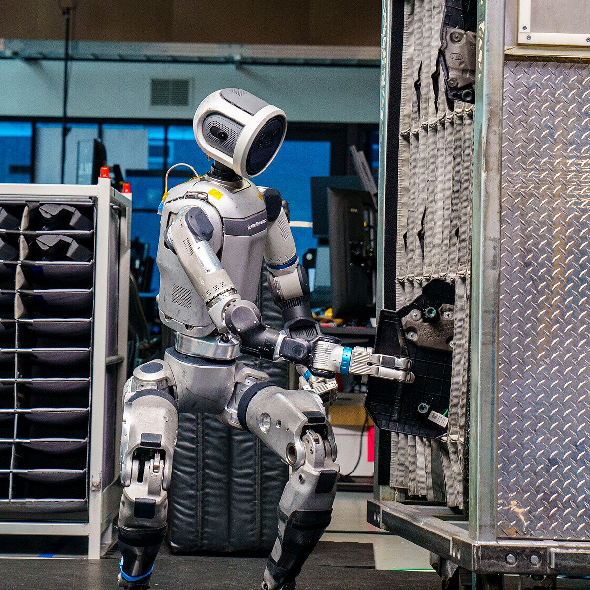 The Atlas robot squats to place an engine cover into a dolly