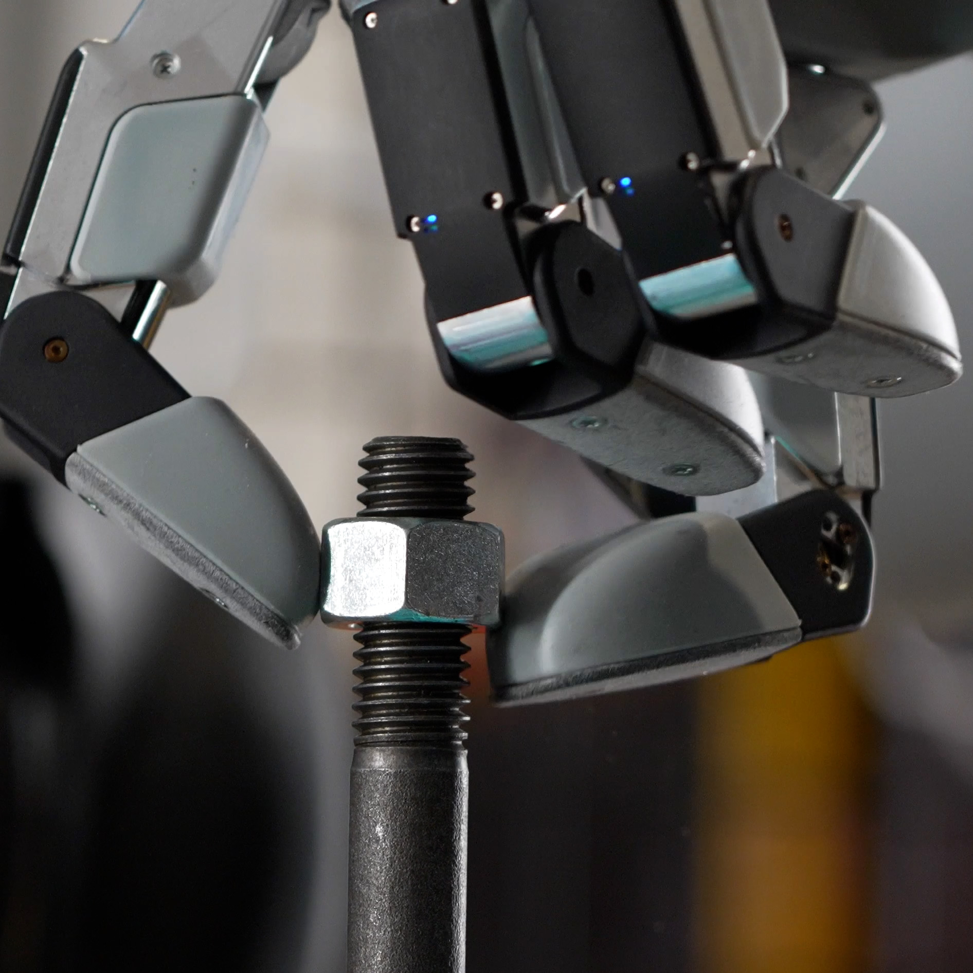 A close up of a robot hand threading a nut onto a bolt